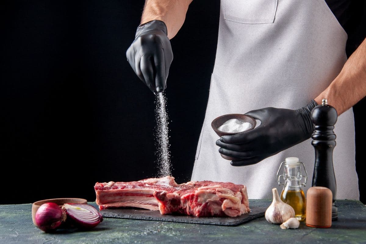 Butcher seasoning a rack of meat