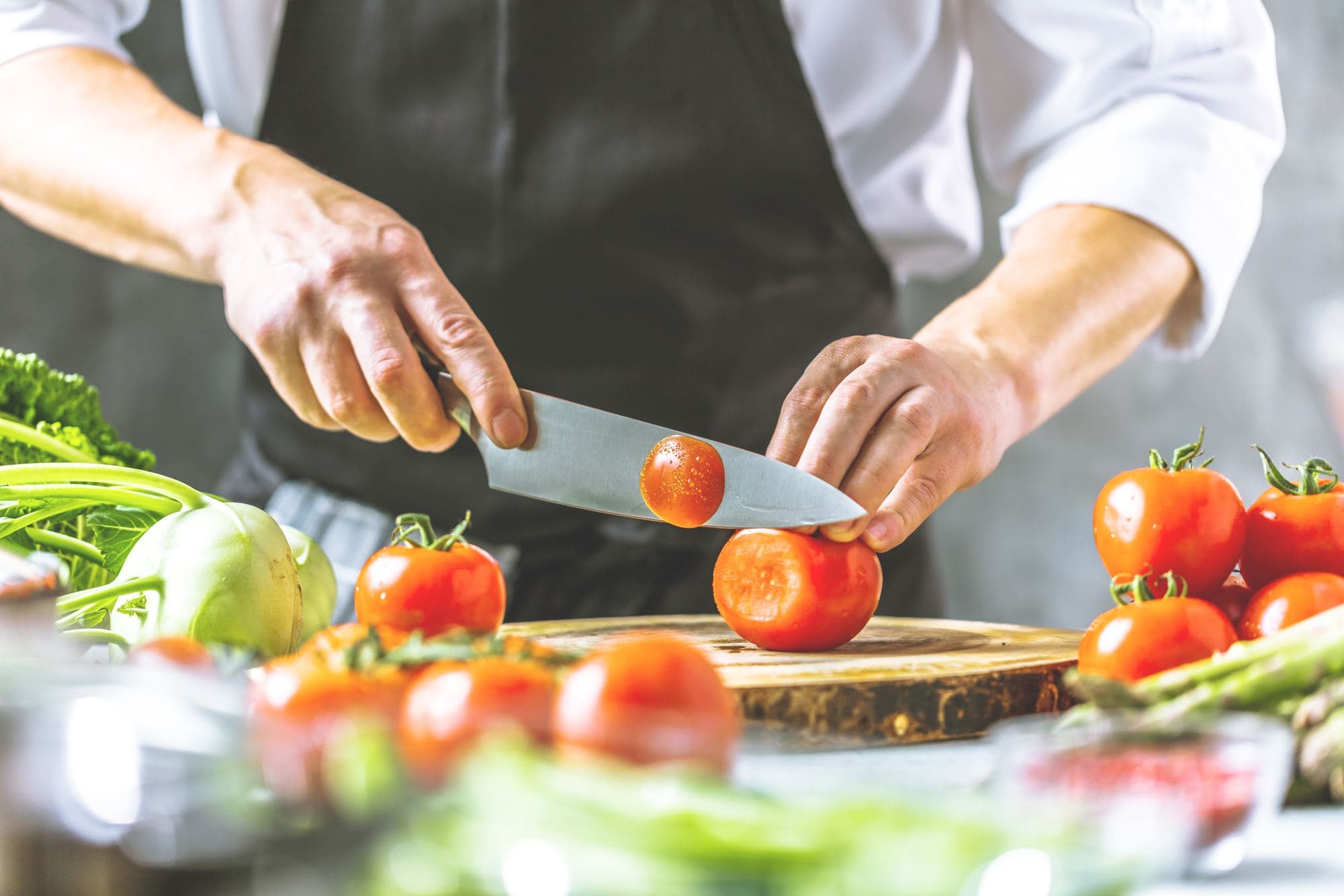 Chef slicing tomatoes on a chopping board