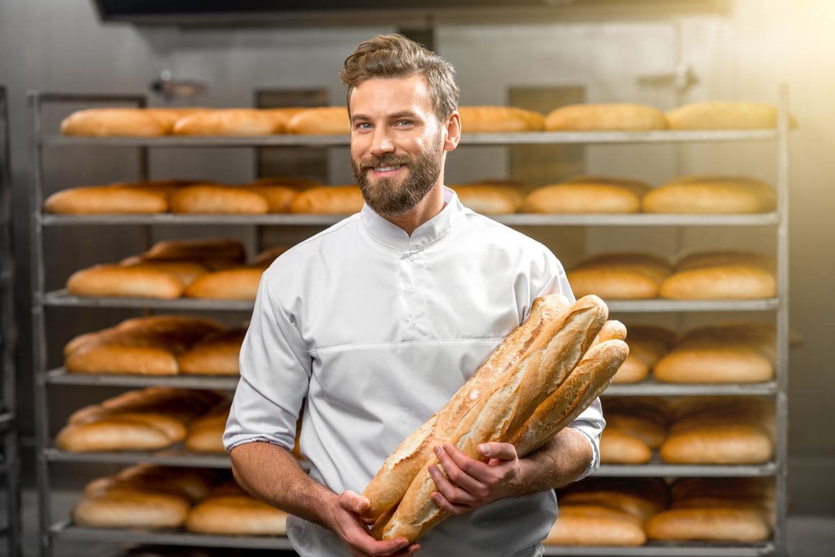Baker in a white jacket holding baguettes