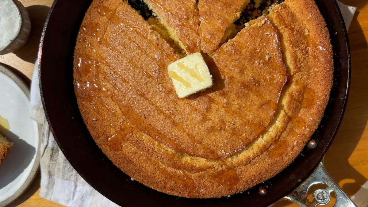 Cornbread baked in a carbon steel skillet, topped with butter