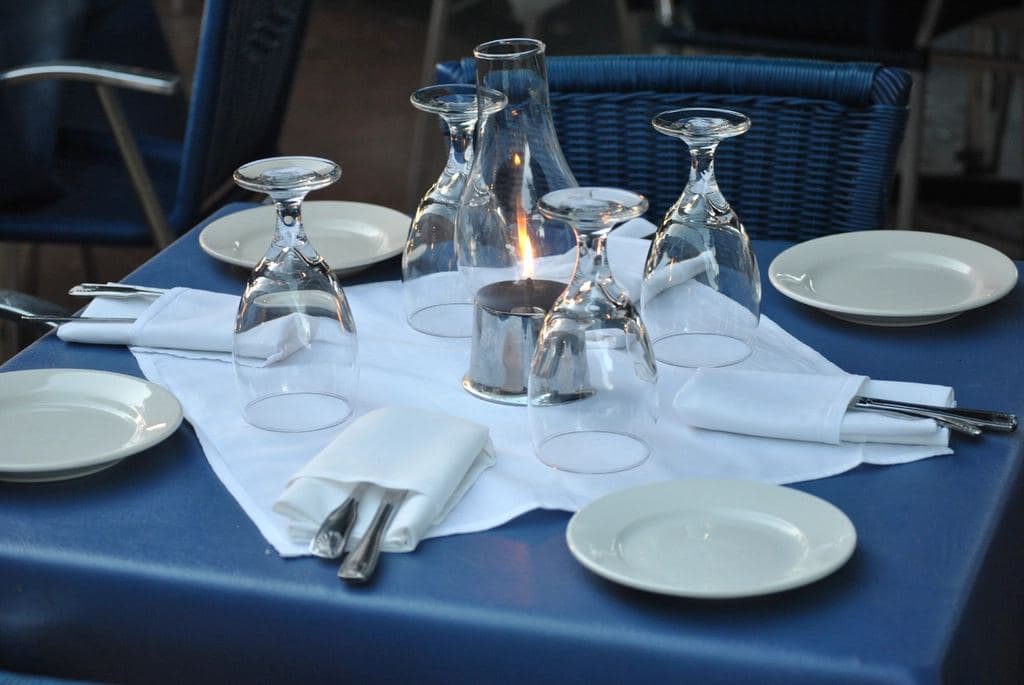 A restaurant table laid with white plates, cutlery and glasses