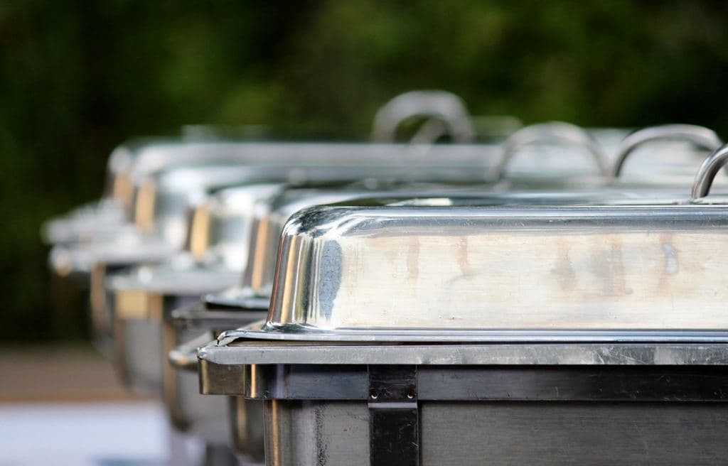 Row of stainless roll-top chafing dishes on a buffet