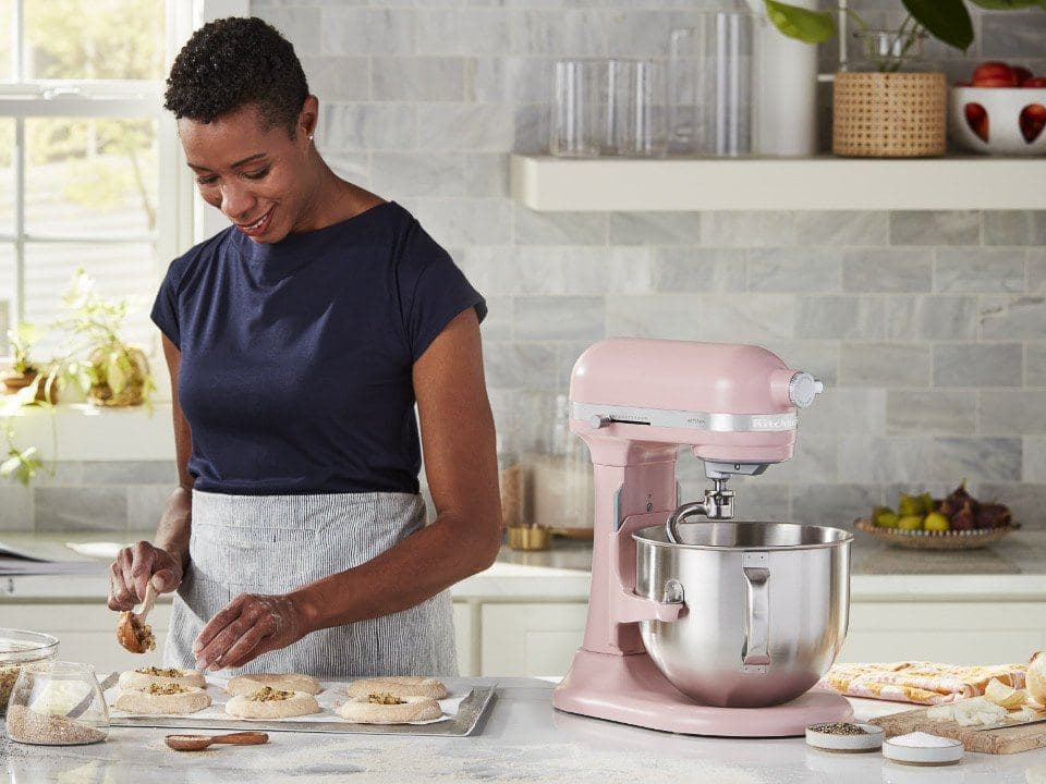 Baker shaping pastries beside a pink KitchenAid bowl-lift mixer