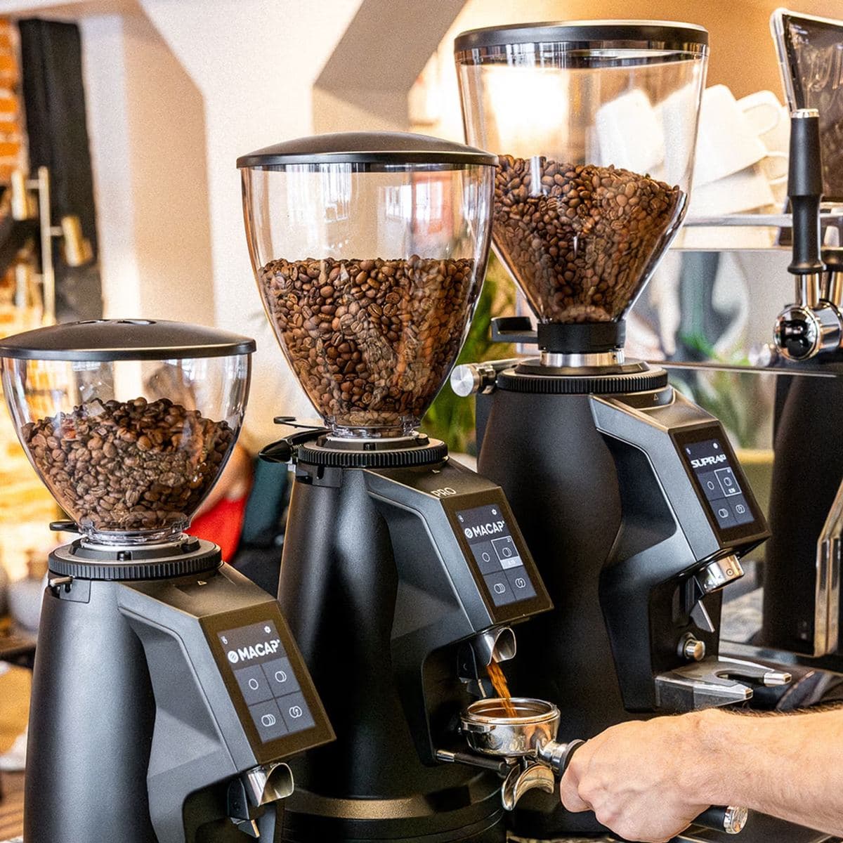 Macap grinders dosing into a portafilter on a café counter