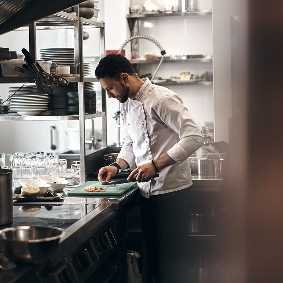 A chef working at the bench in a restaurant kitchen