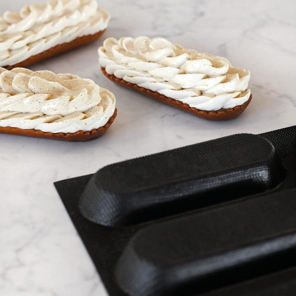 Piped cream pastries beside a Pavoni silicone mould