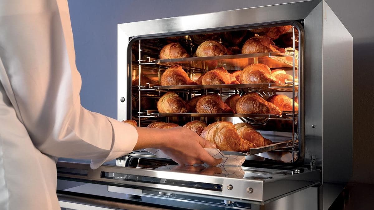 Tray of croissants coming out of a convection oven