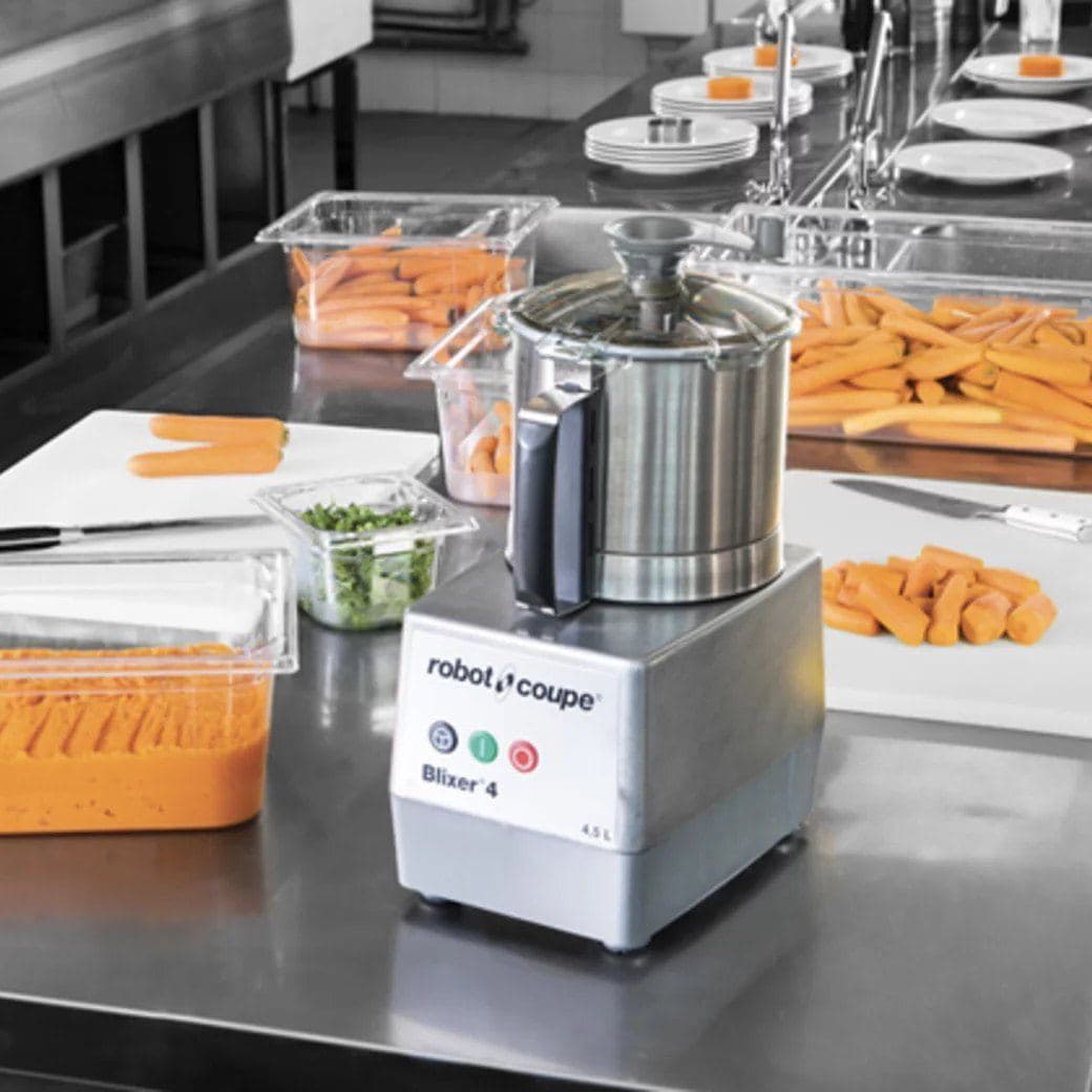 Robot-Coupe cutter beside trays of prepared carrots