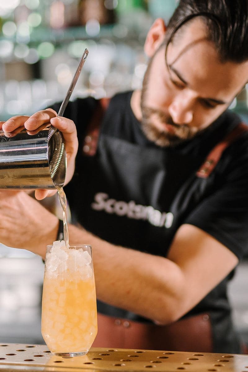 Bartender pouring a cocktail over Scotsman ice